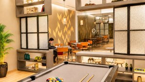 A pool table with balls, a person using a laptop, and a dining area with orange chairs. - Stylish High-Rise Escape: Pool, Hot Tub & Cinema, King-Size Bed and High-Speed WiFi. (Ciudad de México)