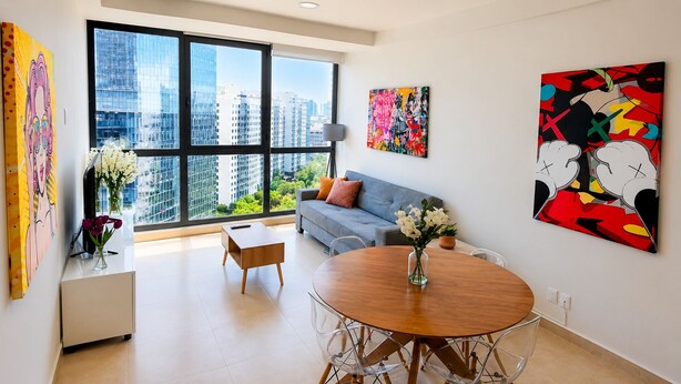 A modern living room with a large window, a round dining table, a sofa, and artwork on the walls. - Stylish High-Rise Escape: Pool, Hot Tub & Cinema, King-Size Bed and High-Speed WiFi. (Ciudad de México)