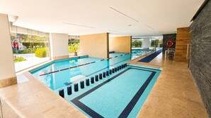 An indoor swimming pool with clear lanes, a lifebuoy, and a view of greenery outside. - Stylish High-Rise Escape: Pool, Hot Tub & Cinema, King-Size Bed and High-Speed WiFi. (Ciudad de México)