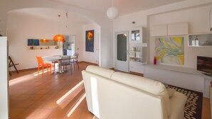 Una sala de estar moderna con un sofá, comedor con sillas y una cocina al fondo.
