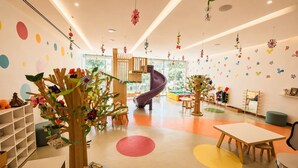 Et legeområde for børn med en rutchebane, farverige vægdekorationer og forskelligt legetøj.