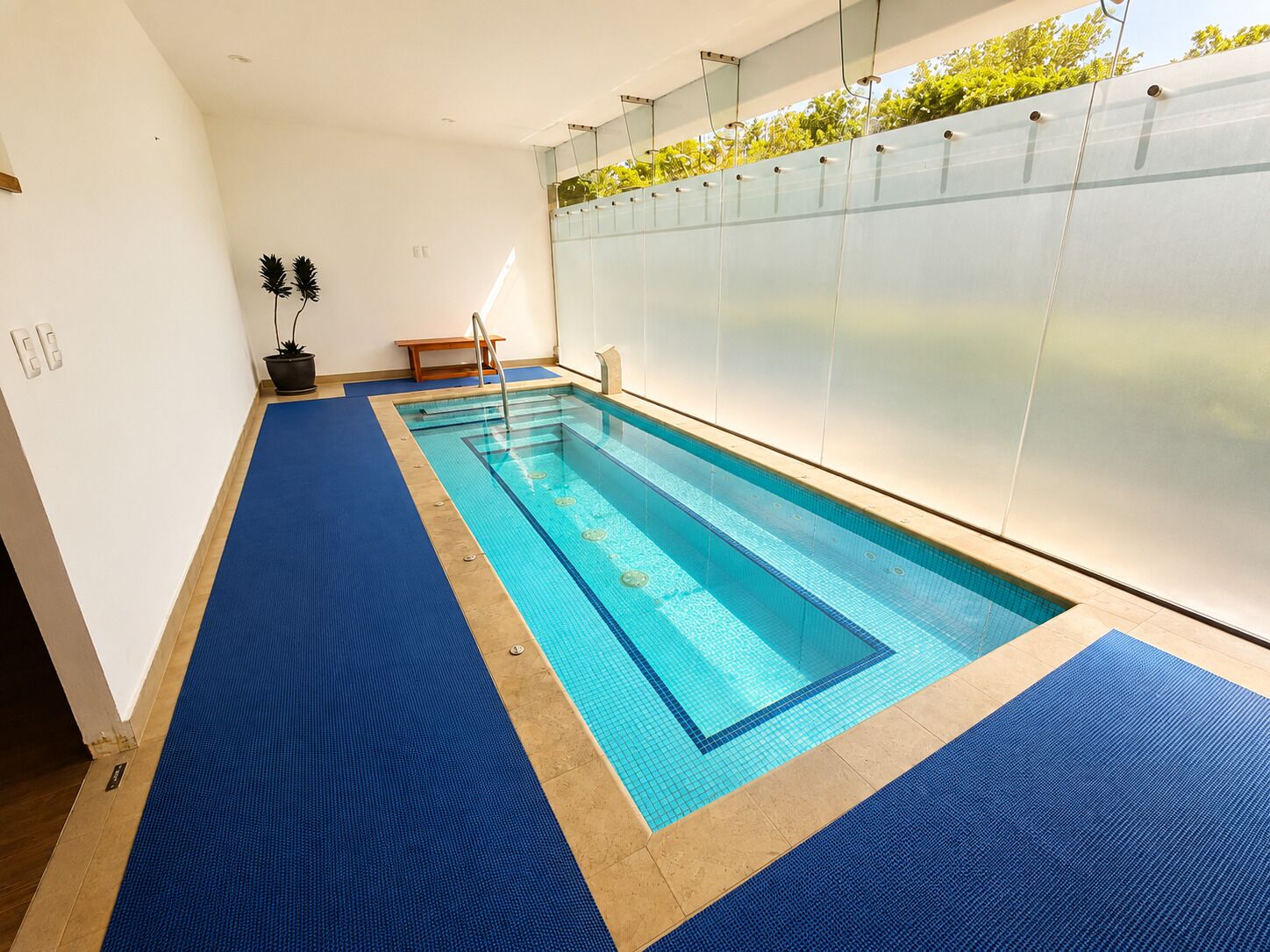 Ein Swimmingpool mit blauer Matte, einer Bank und einem Topfpflanzen.