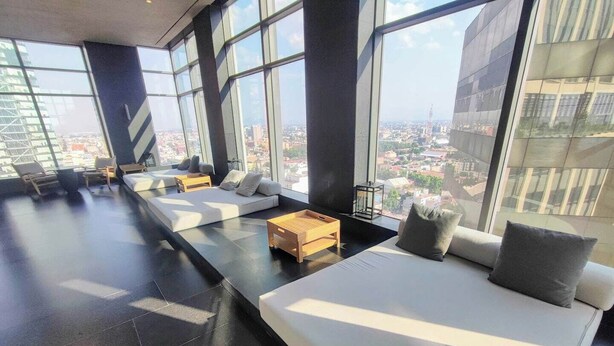 A modern lounge area with large windows, a sofa, and a wooden coffee table.