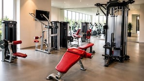 A gym with various exercise machines, a television, and large windows.