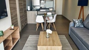 En moderne stue med et træsofabord, en sofa og et spiseområde med hvide stole.