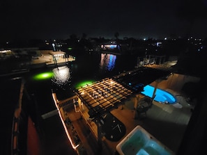 Ein Nachtblick auf ein Anwesen am Wasser mit Pool, überdachter Terrasse und Steg.