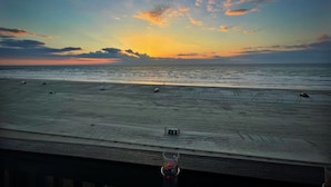Vista de playa con atardecer, vehículos en la arena y cielo despejado.