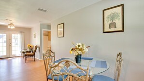 Un comedor con una mesa de vidrio, sillas con cojines azules y un jarrón de flores.