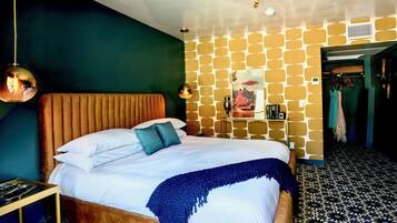 A bedroom with a bed, a wooden headboard, a blue throw blanket, and a patterned floor.