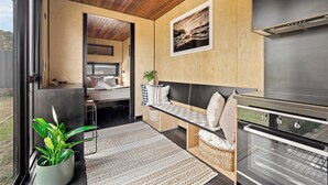 Ein modernes Wohnmobil-Interieur mit Küchenzeile, einer Sitzecke und einem großen Fenster mit Blick ins Freie.