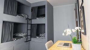 A room with bunk beds, a desk with a laptop, and a potted orchid. - Hostel La Moneda (Santiago)