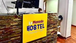 A reception desk with a yellow sign reading "La Moneda HOSTEL Santiago-Chile". - Hostel La Moneda (Santiago)