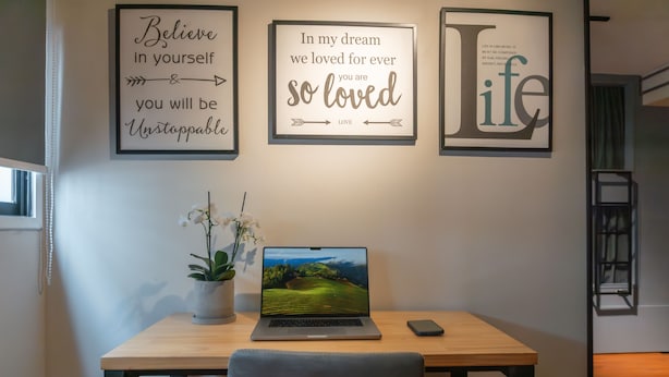 A desk with a laptop, a smartphone, and a potted plant. There are motivational posters on the wall. - Hostel La Moneda (Santiago)