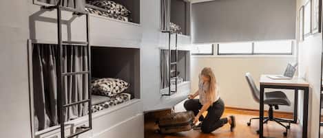 A room with bunk beds, a desk, and a chair.