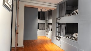 A narrow hallway with wooden flooring leading to a room with bunk beds. - Hostel La Moneda (Santiago)