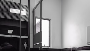 A modern bathroom with a glass shower enclosure, a toilet, and a small window. - Hostel La Moneda (Santiago)