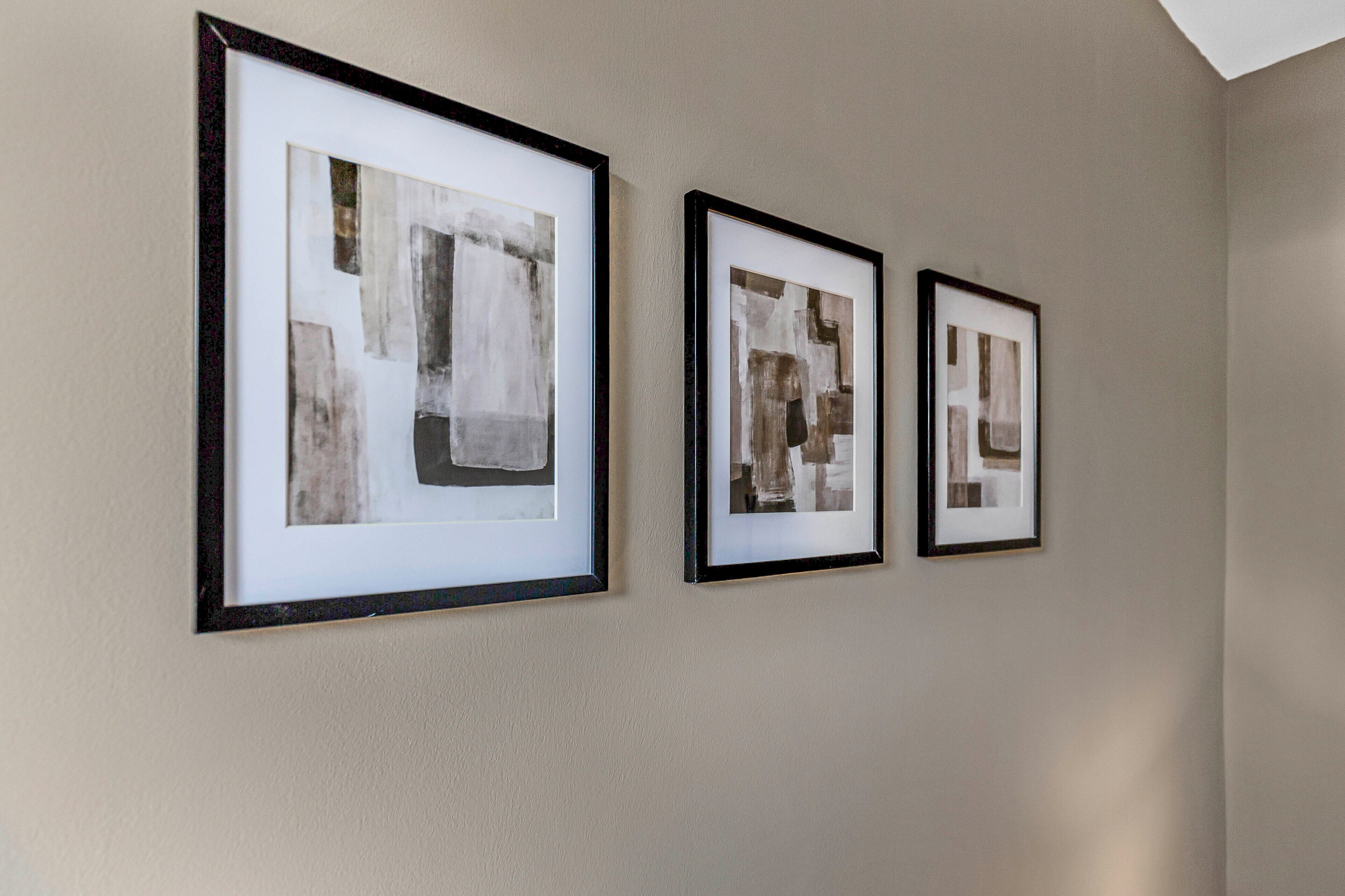 Three framed abstract artworks on a plain wall.