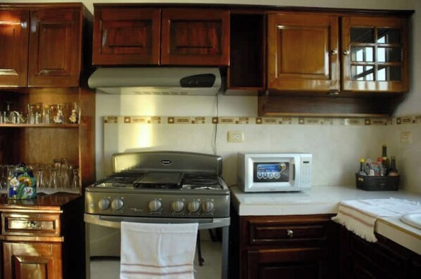 Kitchen area with stove, microwave, and glassware storage.