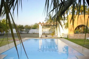 Relax by the serene pool surrounded by lush greenery and a well-maintained lawn.