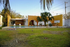 Enjoy a refreshing swim in the pool surrounded by lush greenery and palm trees in the spacious front yard.