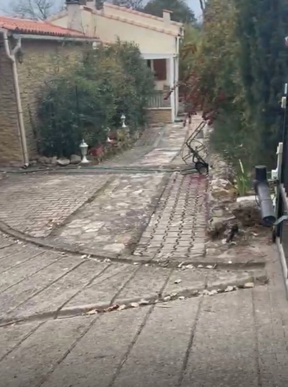 Ein schmaler Steinweg führt zu einem Gebäude mit einem Ziegeldach.