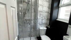Une salle de bain moderne avec une douche à parois de verre, des toilettes et un lavabo.