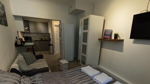 Une chambre à coucher de taille réduite, comprenant un lit, une petite table de chevet et une armoire intégrée.