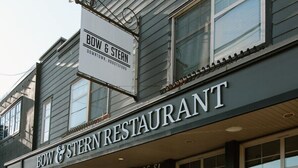 Un restaurant appelé « BOW & STERN RESTAURANT », avec une enseigne au-dessus de l’entrée et une grande affiche sur la façade du bâtiment.