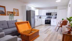 Une cuisine moderne avec des meubles blancs, des appareils en acier inoxydable et un coin repas comprenant une table et des chaises en bois.