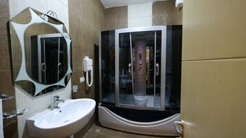 A bathroom with a white sink, a large mirror, and a glass-enclosed shower area.
