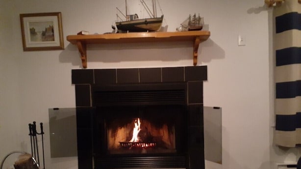Una chimenea con repisa decorativa, un cuadro enmarcado en la pared y una cortina a rayas a la derecha.
