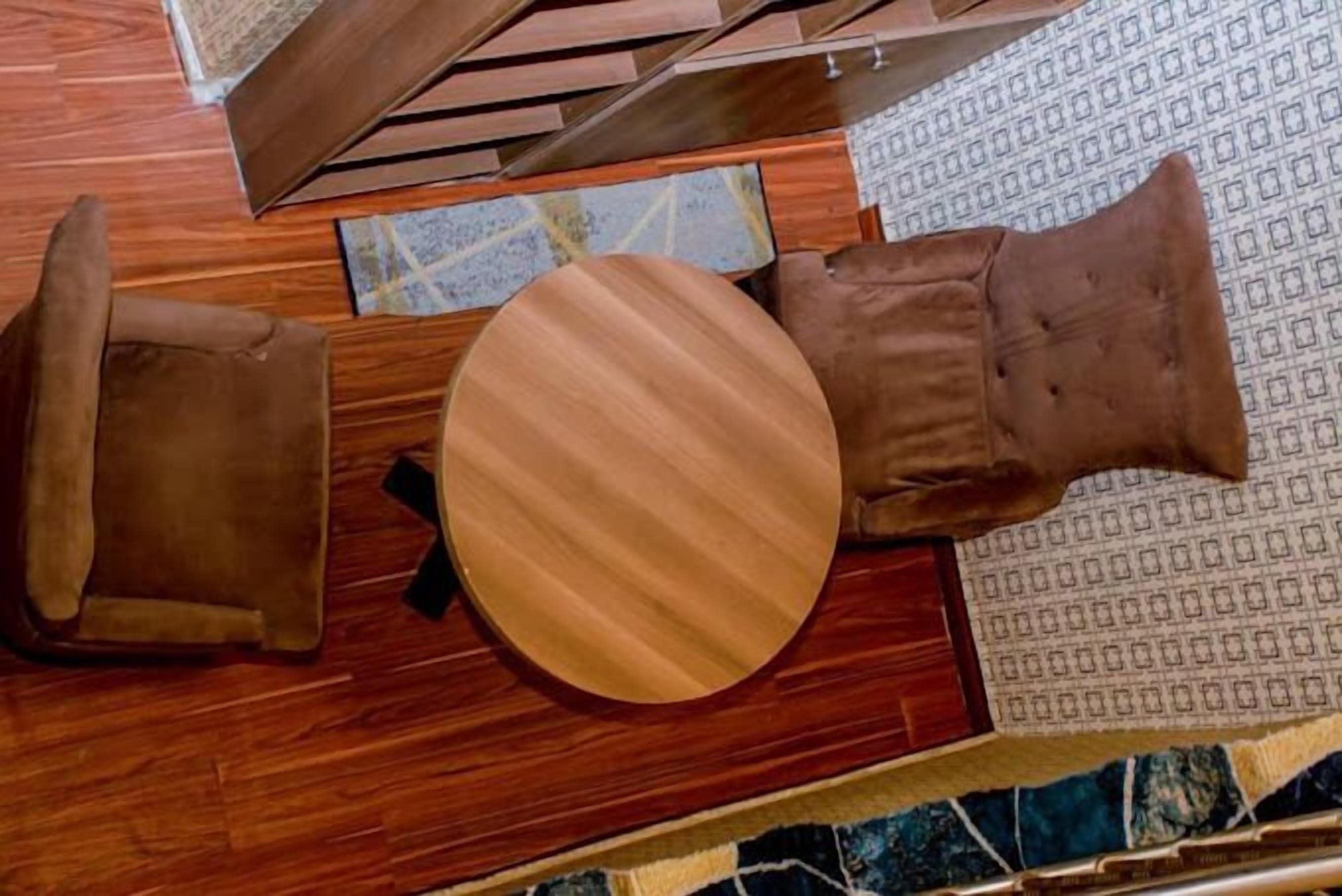 Una habitación con piso de madera, una mesa redonda de madera y dos sillas de cuero marrón.