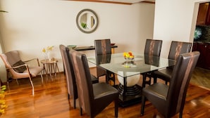A dining area with a glass table surrounded by leather chairs, a small side table with a vase, and a mirror on the wall.