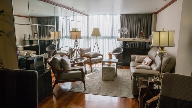 A modern living room with a sofa, armchairs, a coffee table, and a TV.