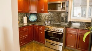 A kitchen with wooden cabinets, a stainless steel stove, a microwave, and granite countertops.
