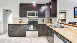 A modern kitchen with dark cabinets, a stainless steel stove, and a microwave.
