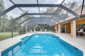 Une piscine couverte avec des chaises longues, un espace barbecue et une terrasse avec des sièges d’extérieur.