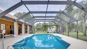 An indoor swimming pool with a glass ceiling, surrounded by a covered patio area.