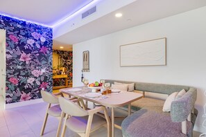 A dining area with a table set for four, a sofa, and a decorative wall with floral patterns.