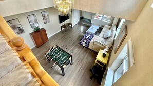 A spacious living area with a foosball table, a sofa, a coffee table, and a chandelier. - Relax @ Retreat Pool Hot Tub Billiards Game SF Bay (Santa Clara)