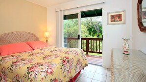 Een slaapkamer met een bed, nachtkastje, lamp, raam en balkon.