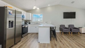 Una cocina moderna con electrodomésticos de acero inoxidable, una isla central y una zona de estar con dos sillas.