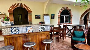 A bar area with a wooden counter, three stools, and a sign that reads "WELCOME". - Hotel Yamilí (Punta Cana)