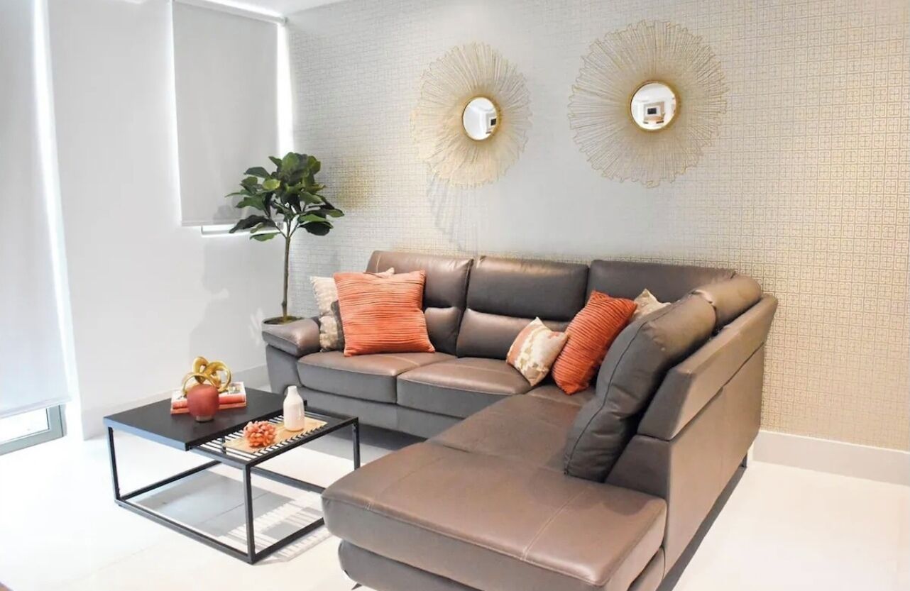 Una sala de estar moderna con un sofá modular, una mesa de centro y apliques decorativos en la pared.