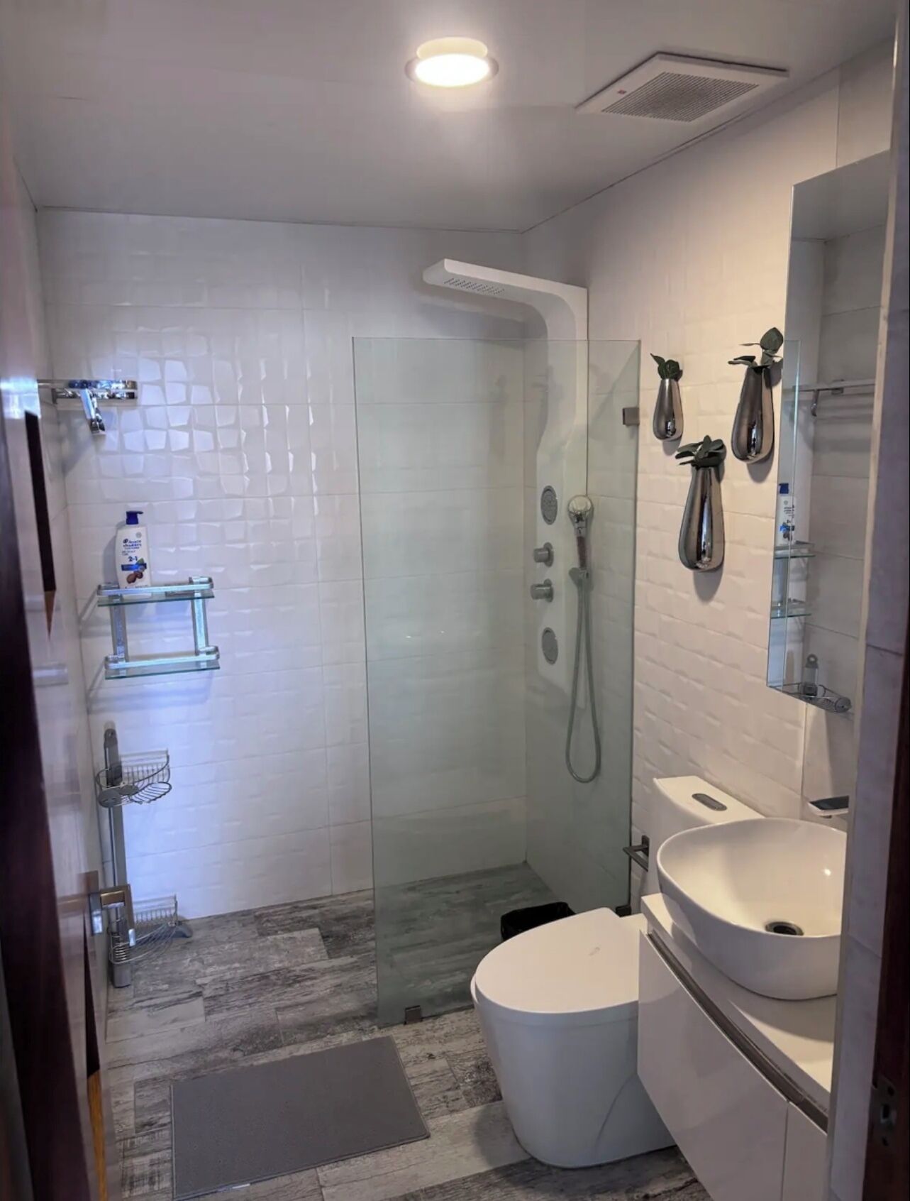 A modern bathroom with a glass-enclosed shower, a white sink, and a toilet.