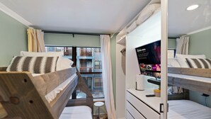 A hotel room with two bunk beds, a small desk with a computer, and a large window with curtains. - Downtown Breck Base Camp — Walk to Main St & Gondola — Pool + Hot Tubs (Breckenridge)