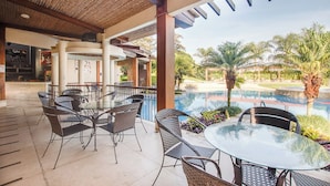 An outdoor patio area with a pool, dining tables, and chairs.