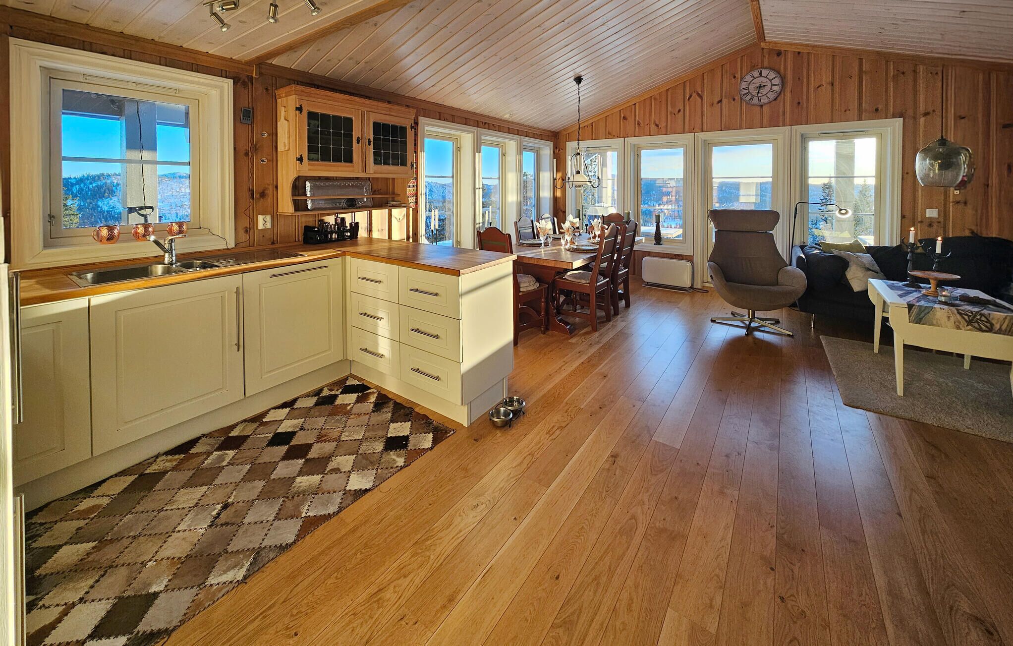 Una cocina amplia con armarios de madera, un comedor con mesa y sillas, y una sala de estar acogedora con sofá y mesa de centro.