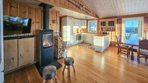 A cozy cabin interior with a wood-burning stove, a television, and a dining area.
