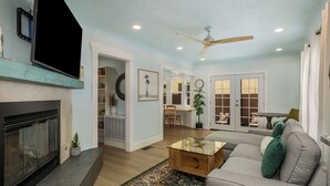 Ein Wohnzimmer mit Kamin, Deckenventilator, einer Couch und einem Couchtisch.
